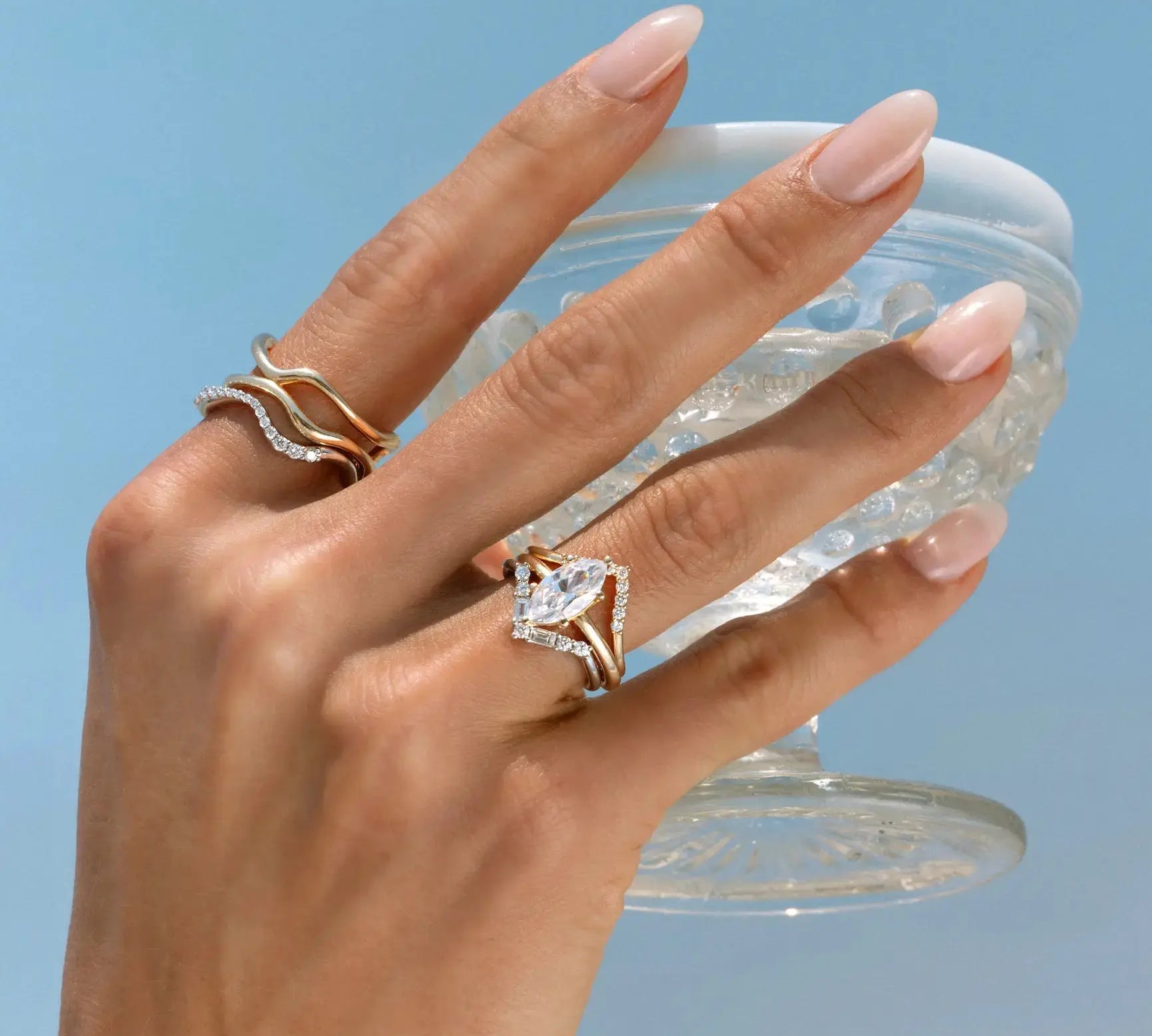 Hand holding a clear container with crystals against a light blue background