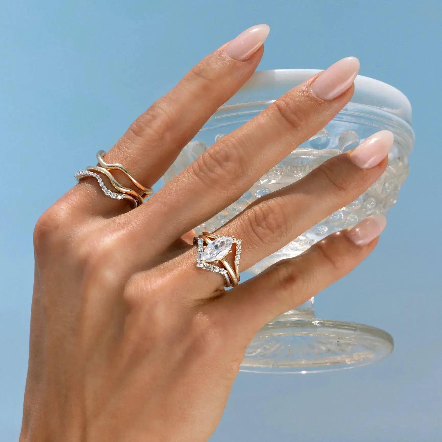 Hand holding a clear container with crystals against a light blue background