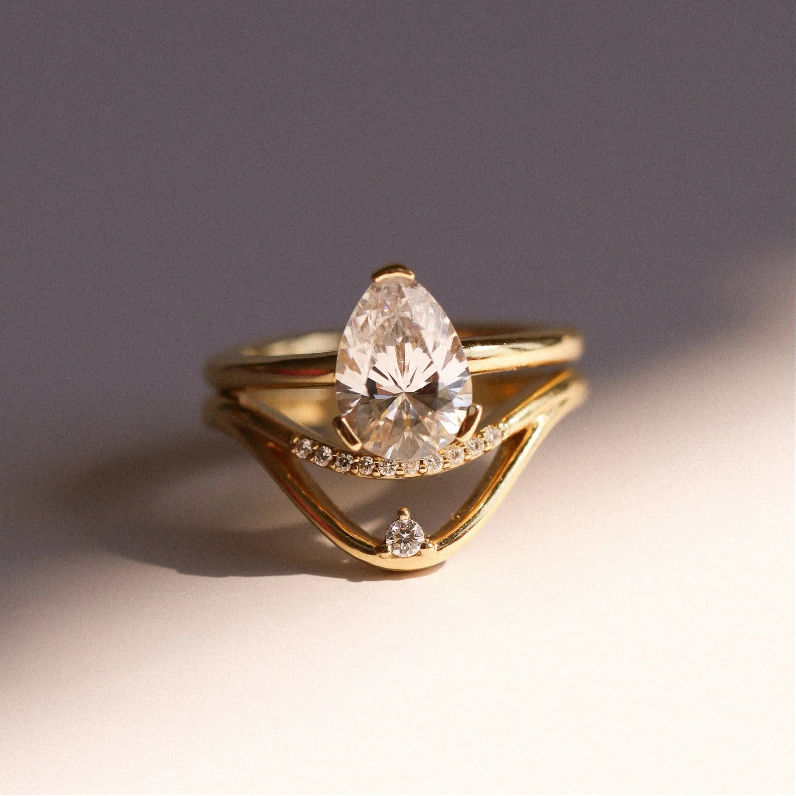 Gold ring with a pear-shaped diamond on a gradient background
