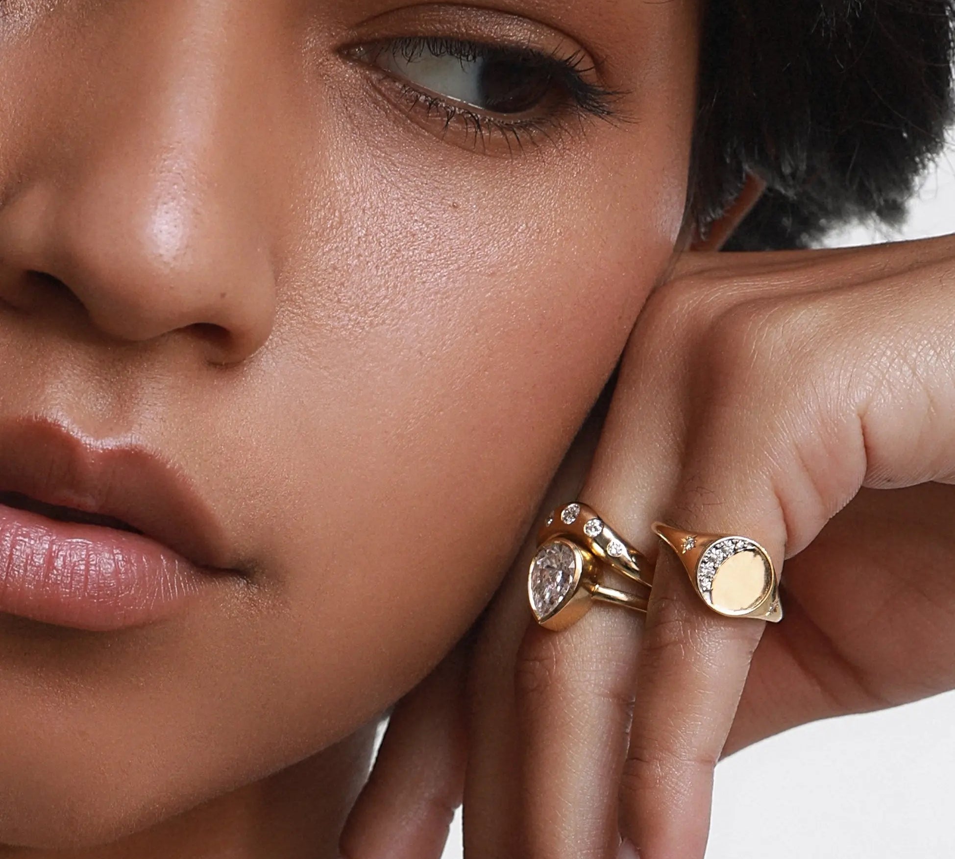 Close up of woman resting her hand against her face, featuring multiple Marrow Fine rings styled 