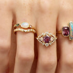 Close-up of fingers wearing multiple rings with gemstones on a light skin background