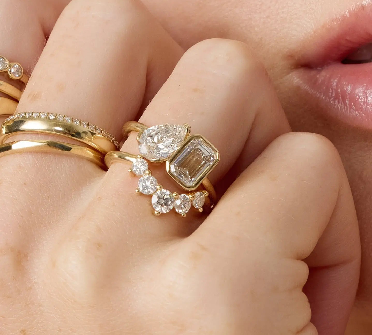 Close-up of a hand wearing multiple gold and diamond rings.