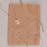 Flat lay on blush tissue paper: White Diamond La Femme pendant, Coco Tennis Bracelet, White Diamond Orbit Studs, Opal Lotus Studs and Dainty Diamond Bezel Bracelet