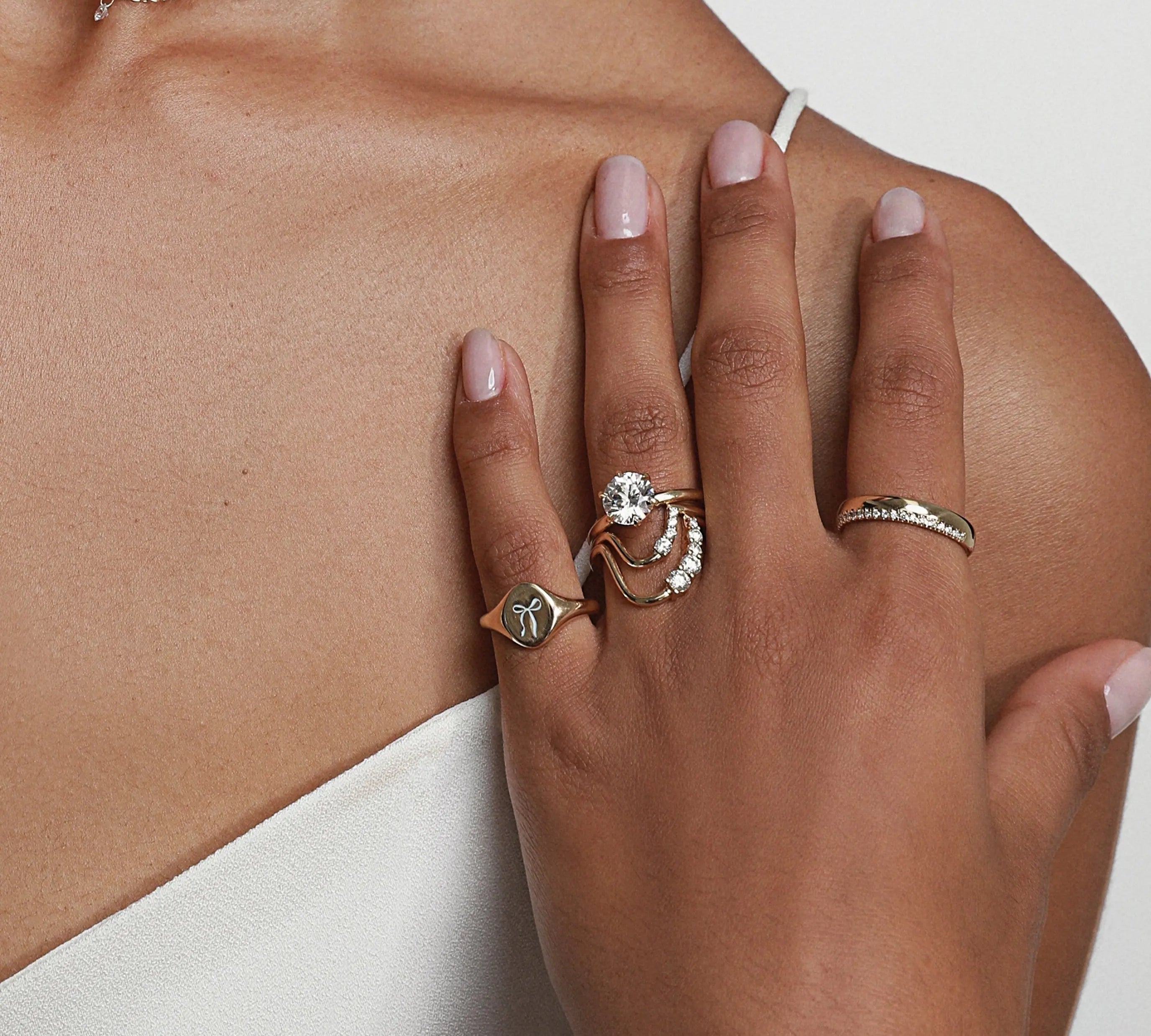 close up of woman's hand against her décolletage featuring multiple Marrow Fine rings styled