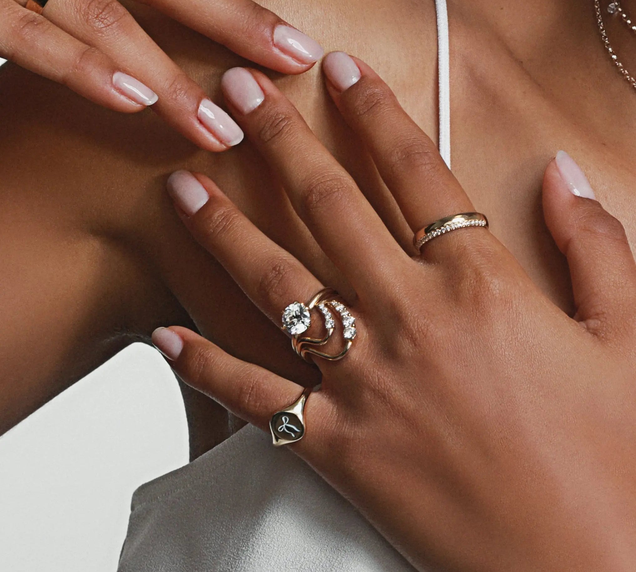 close up of woman's hands resting against her décolletage featuring multiple Marrow Fine rings styled