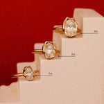 three abstract bezel diamond engagement rings with varying carat weights on a small stepping latter, with a red background