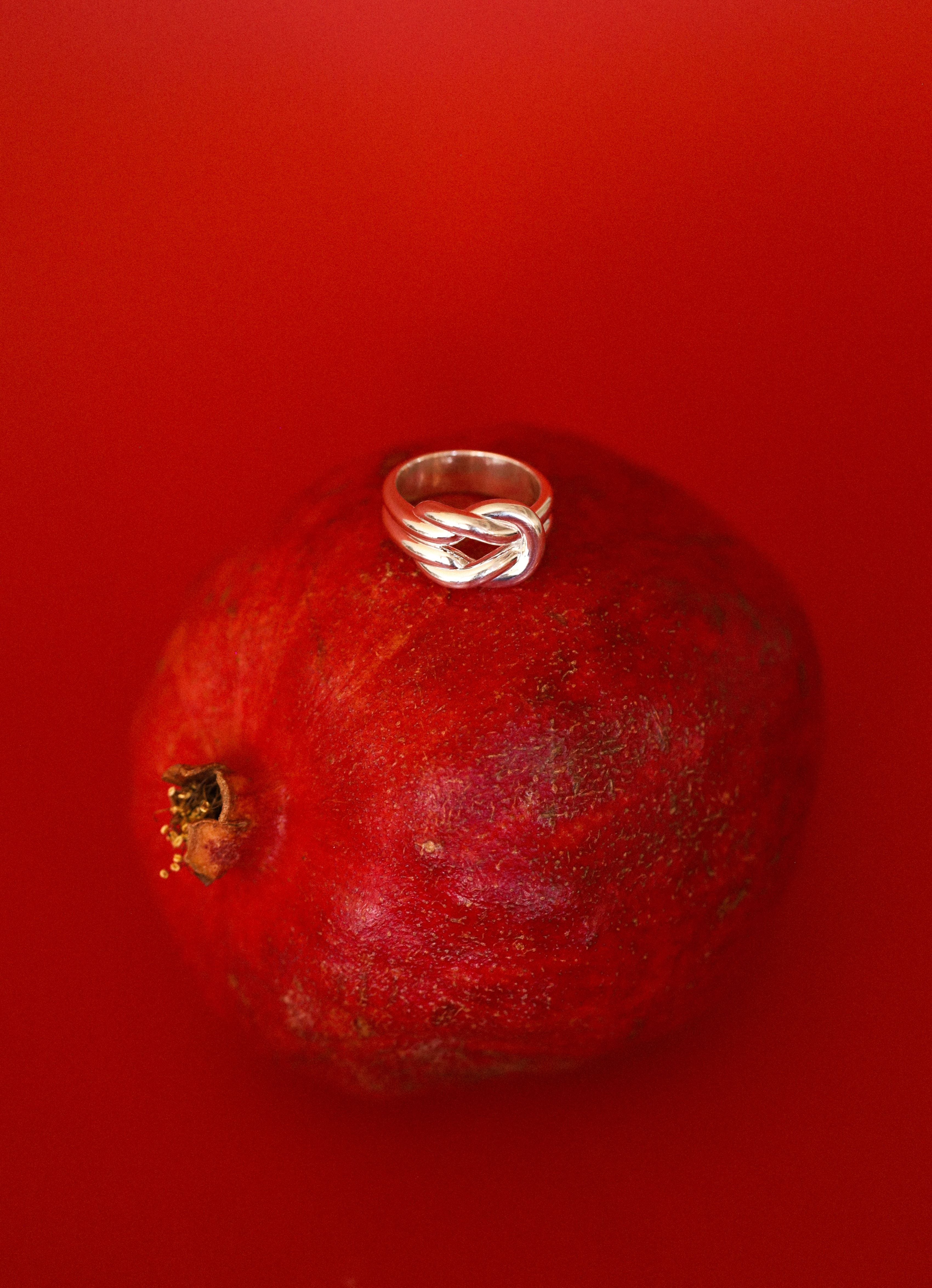 Silver ring on a pomegranate against a red background