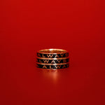 Three black enamel Always Gold Memory Rings stacked on top of each other against a red backdrop