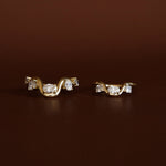 Pair of gold earrings with diamond accents on a brown background