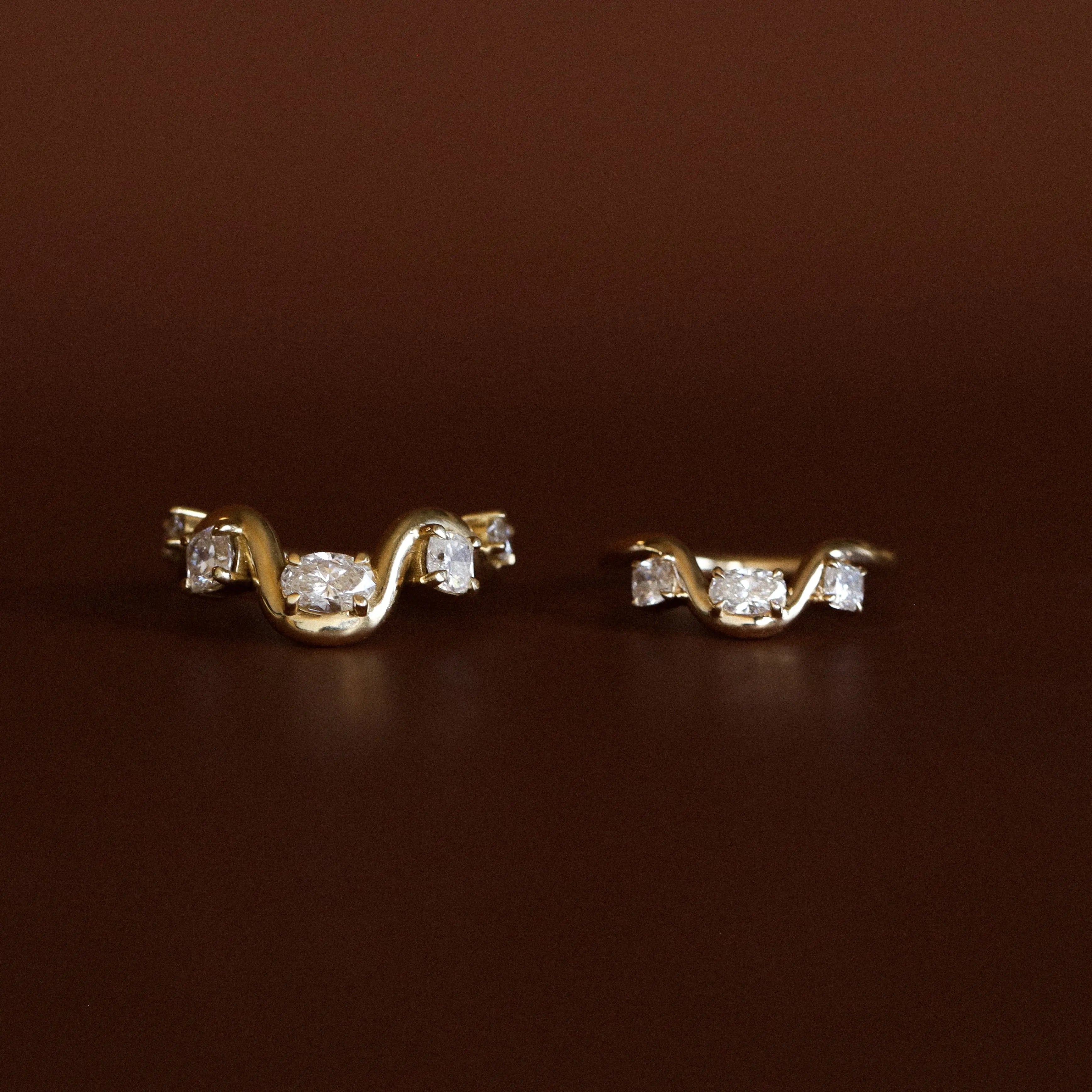 Pair of gold earrings with diamond accents on a brown background