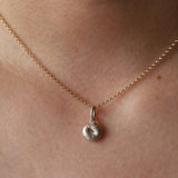 Silver Bagel Charm on yellow gold dainty chain hanging from woman's neck