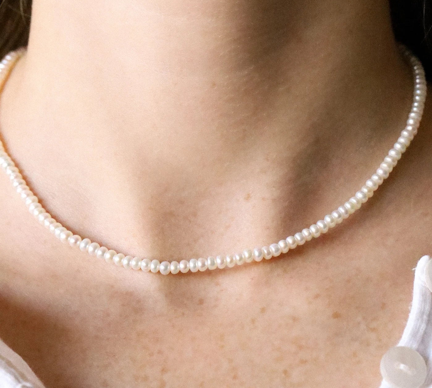 Pearl necklace worn by a person with a white top