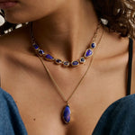 close up of woman's décolletage showcasing two statement blue gemstone necklaces layered together