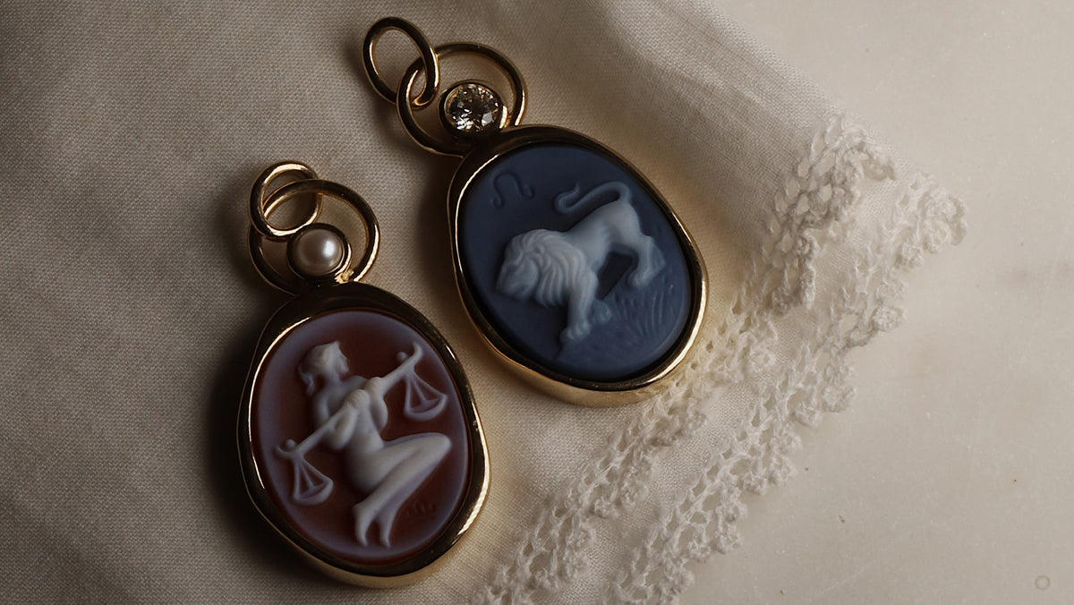 Libra and Leo Zodiac pendants against a white handkerchief