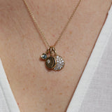 Necklace with three charms on a person wearing a white top