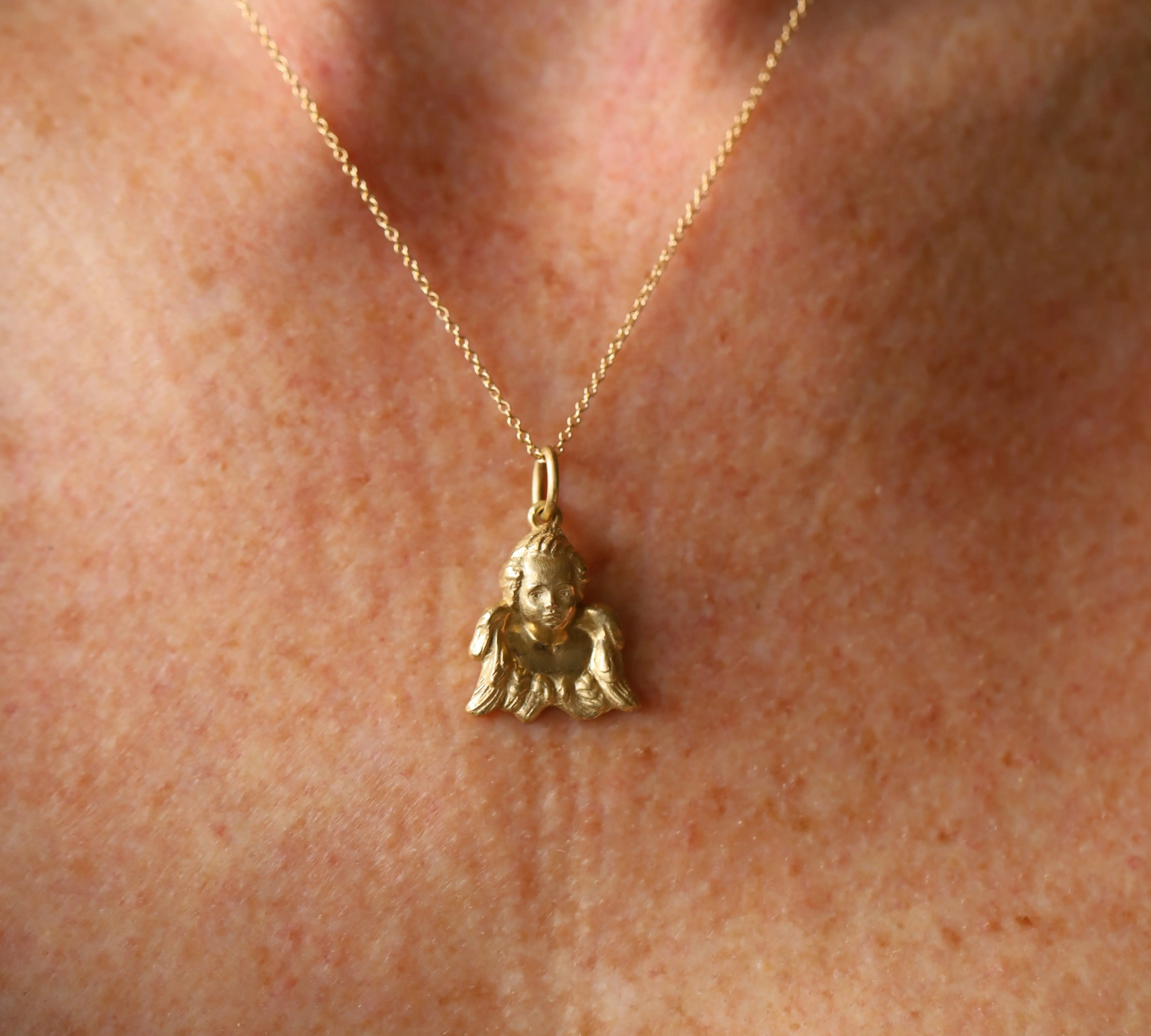 Gold necklace with a small pendant on a person's neck