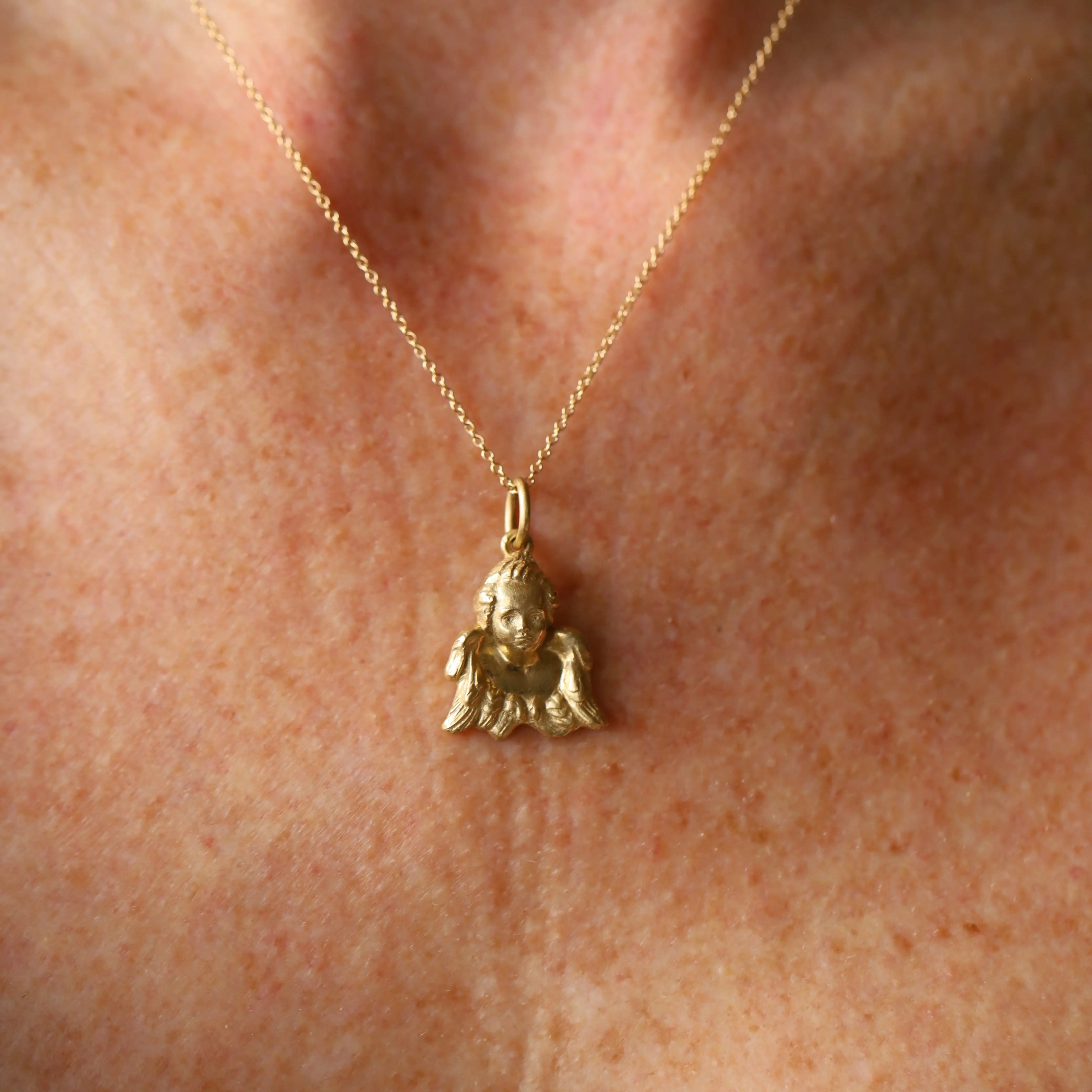 Gold necklace with a small pendant on a person's neck