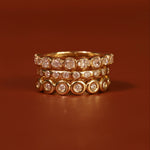 Stack of gold rings with diamond accents on a brown background