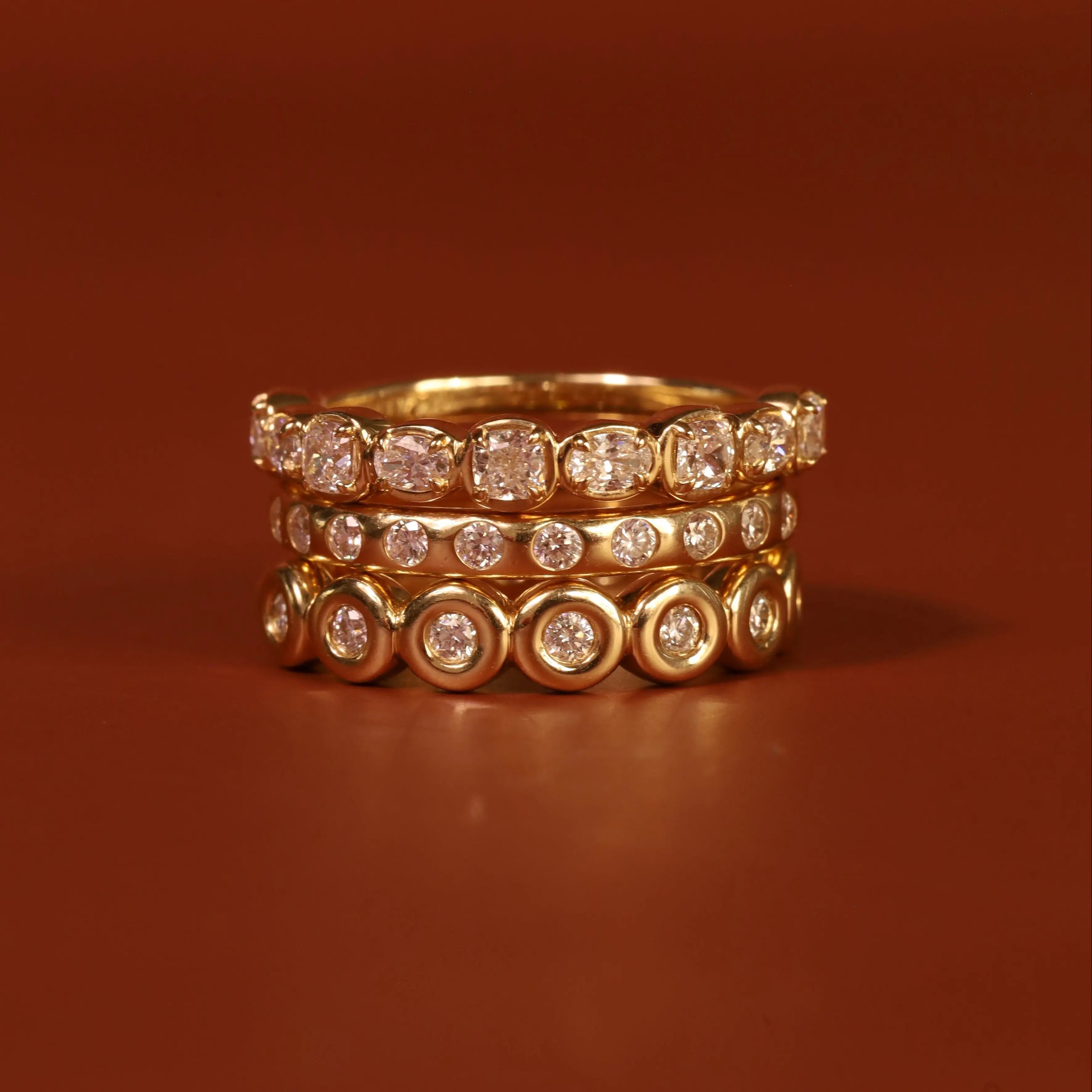 Stack of gold rings with diamond accents on a brown background