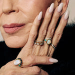 Close-up of a woman's hands with multiple rings on a neutral background