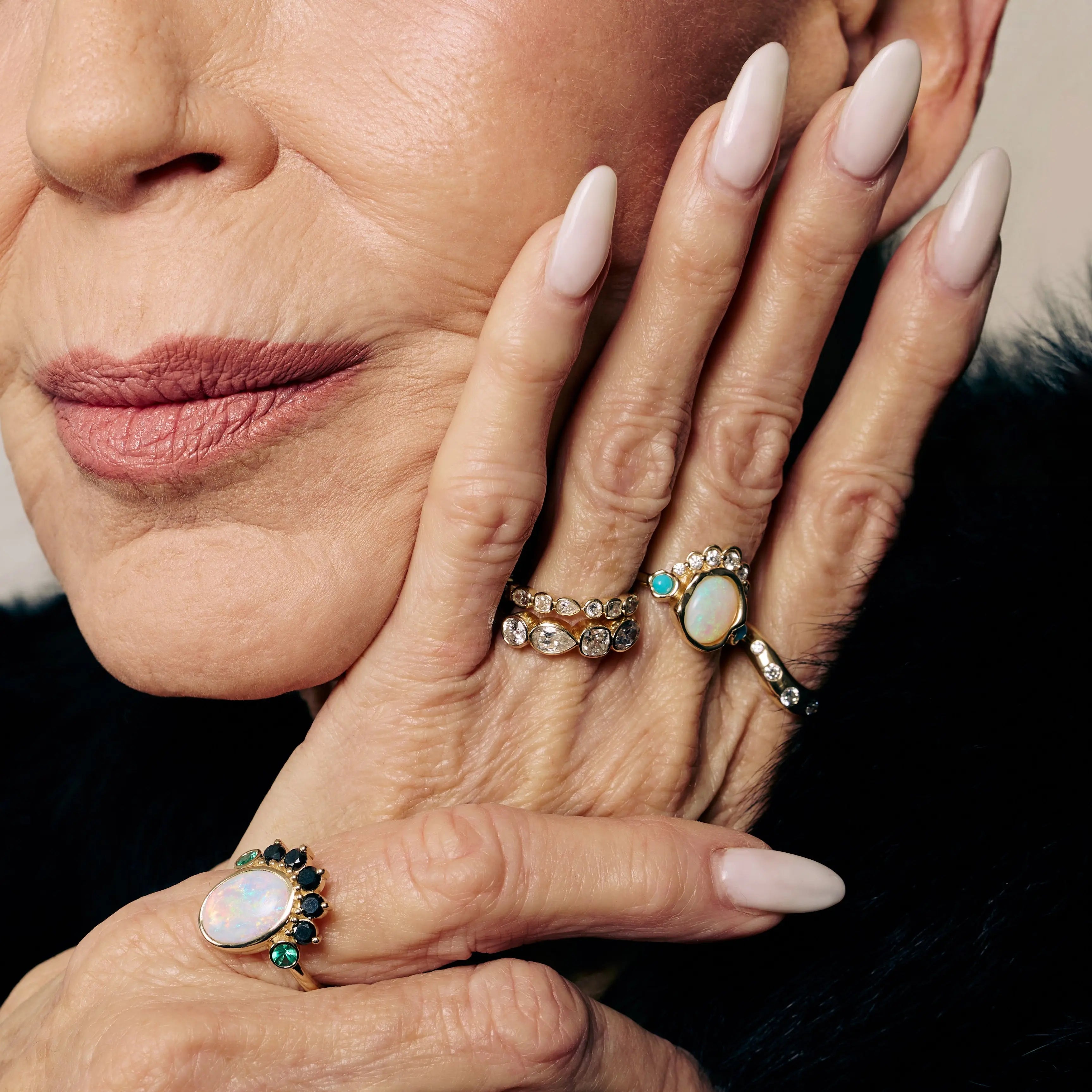 Close-up of a woman's hands with multiple rings on a neutral background