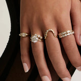 Hand wearing Marrow Fine diamond stacking rings across four fingers, including a round diamond cluster ring, a curved wave band and diamond eternity bands