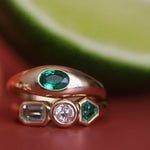 Gold ring with green gemstone on a red and green background