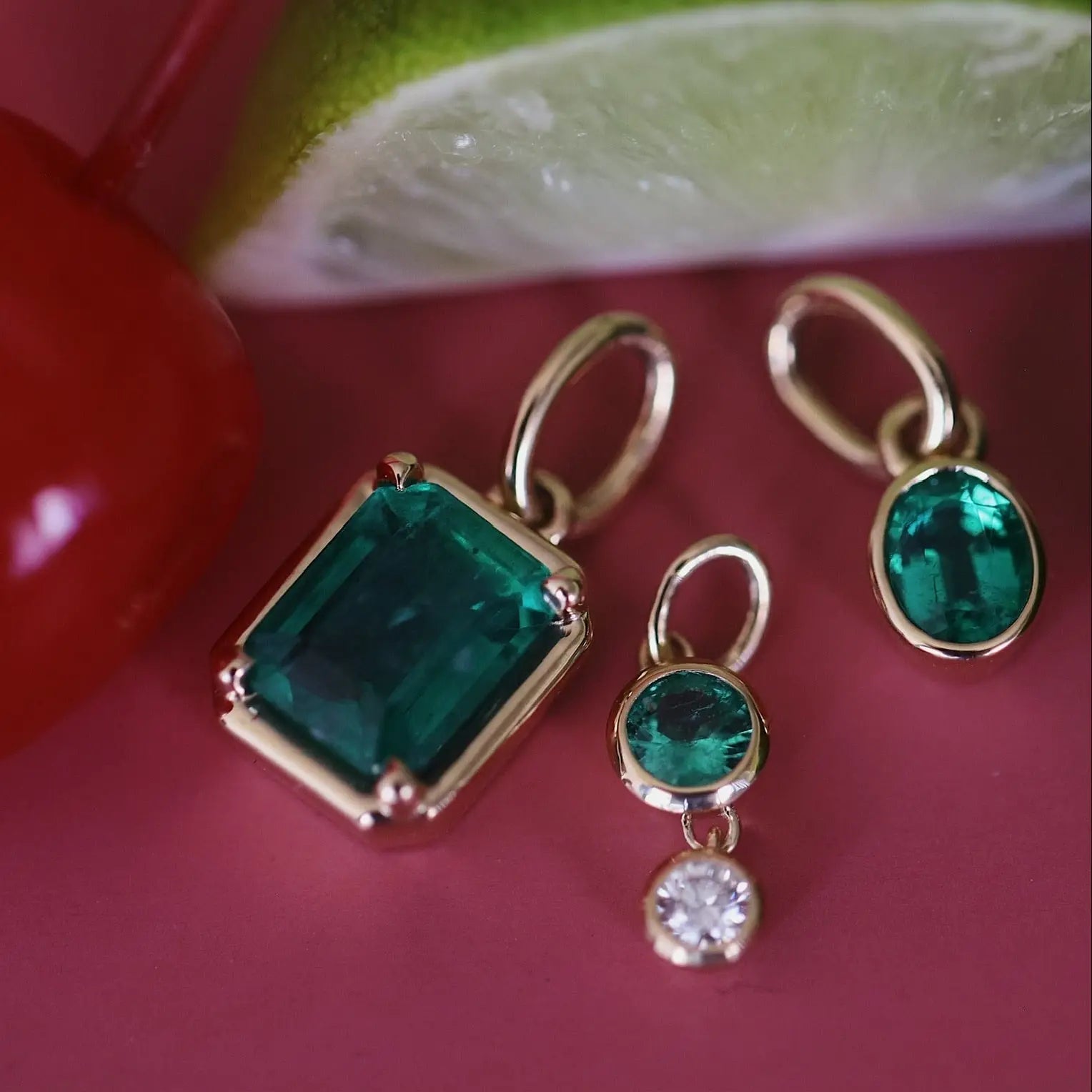 Gold earrings with green gemstones on a red surface