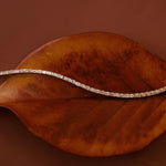 Evert Emerald Lab Created Tennis Bracelet styled over a leaf against a brown-red background