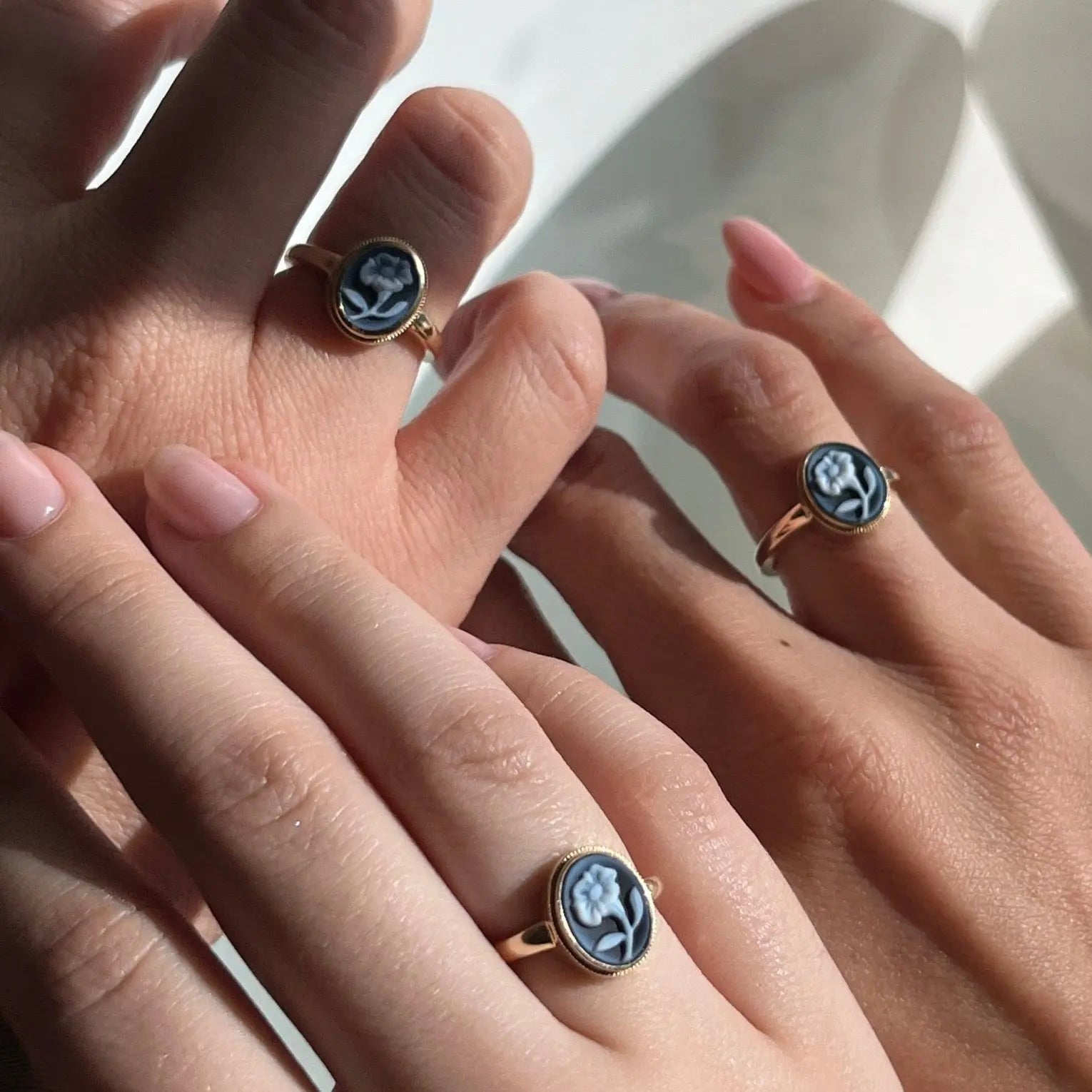 close up of three hands with blue cameo flower ring