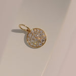 Gold pendant with diamond stones on a beige background