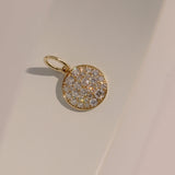 Gold pendant with diamond stones on a beige background