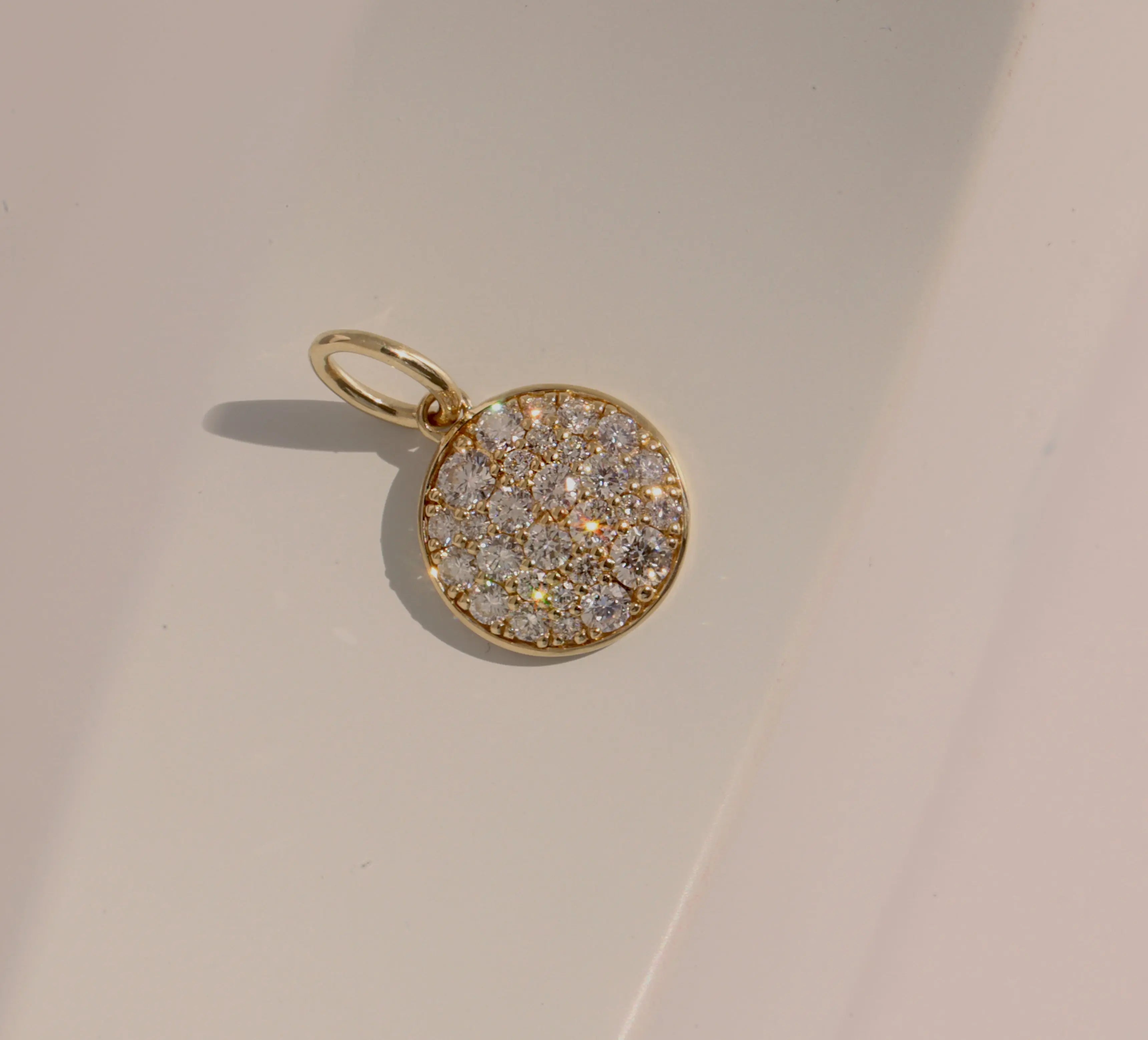 Gold pendant with diamond stones on a beige background
