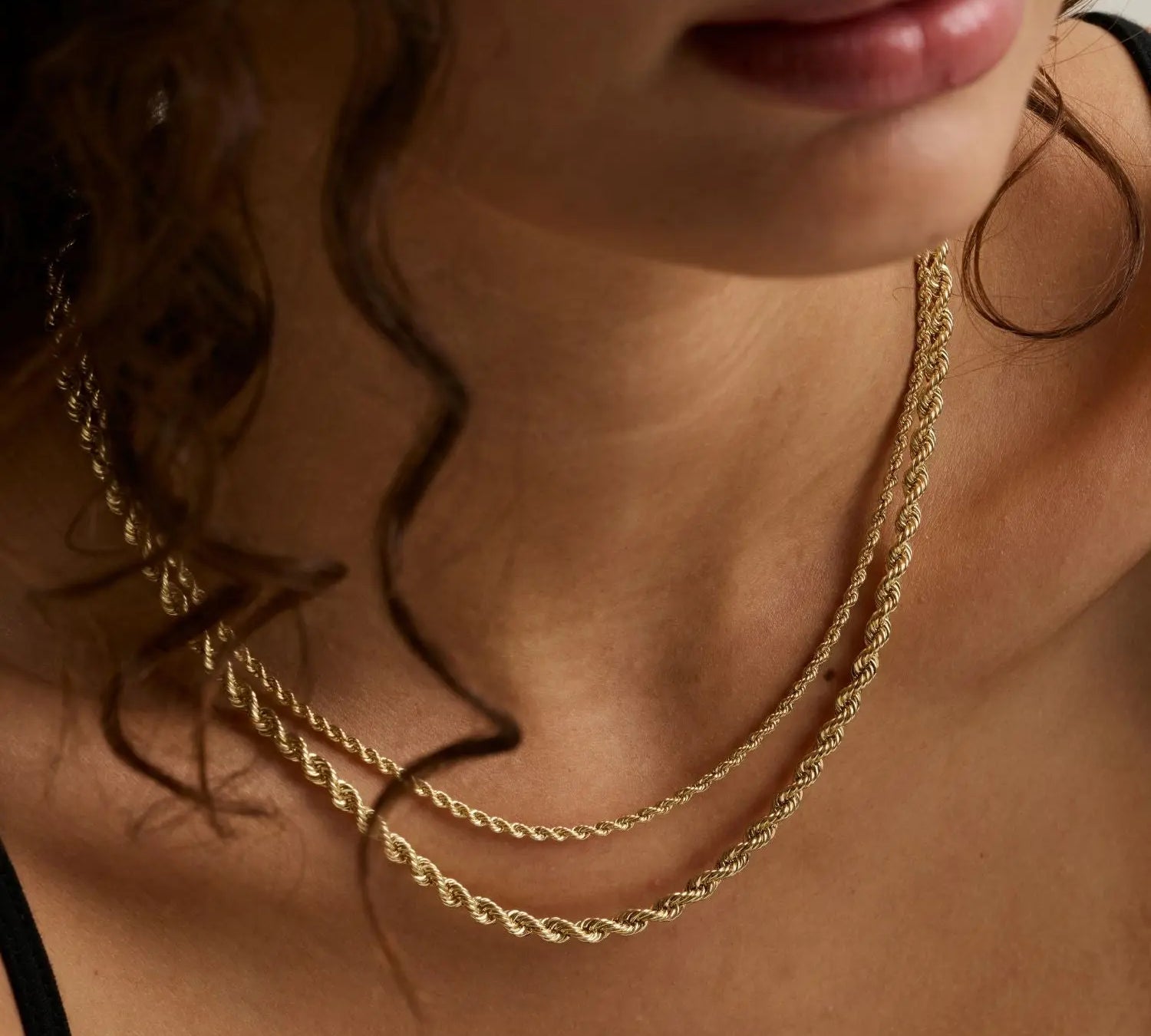 close up of woman's décolletage wearing two layered yellow gold rope chains