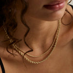 close up of woman's décolletage wearing two layered yellow gold rope chains