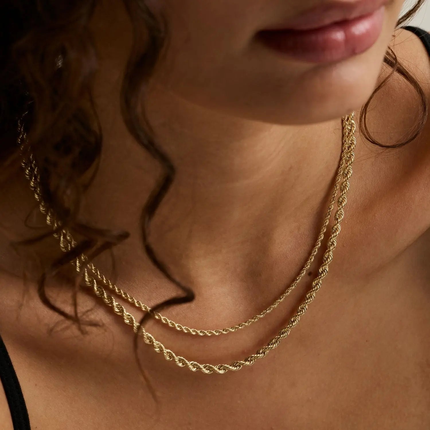 close up of woman's décolletage wearing two layered yellow gold rope chains