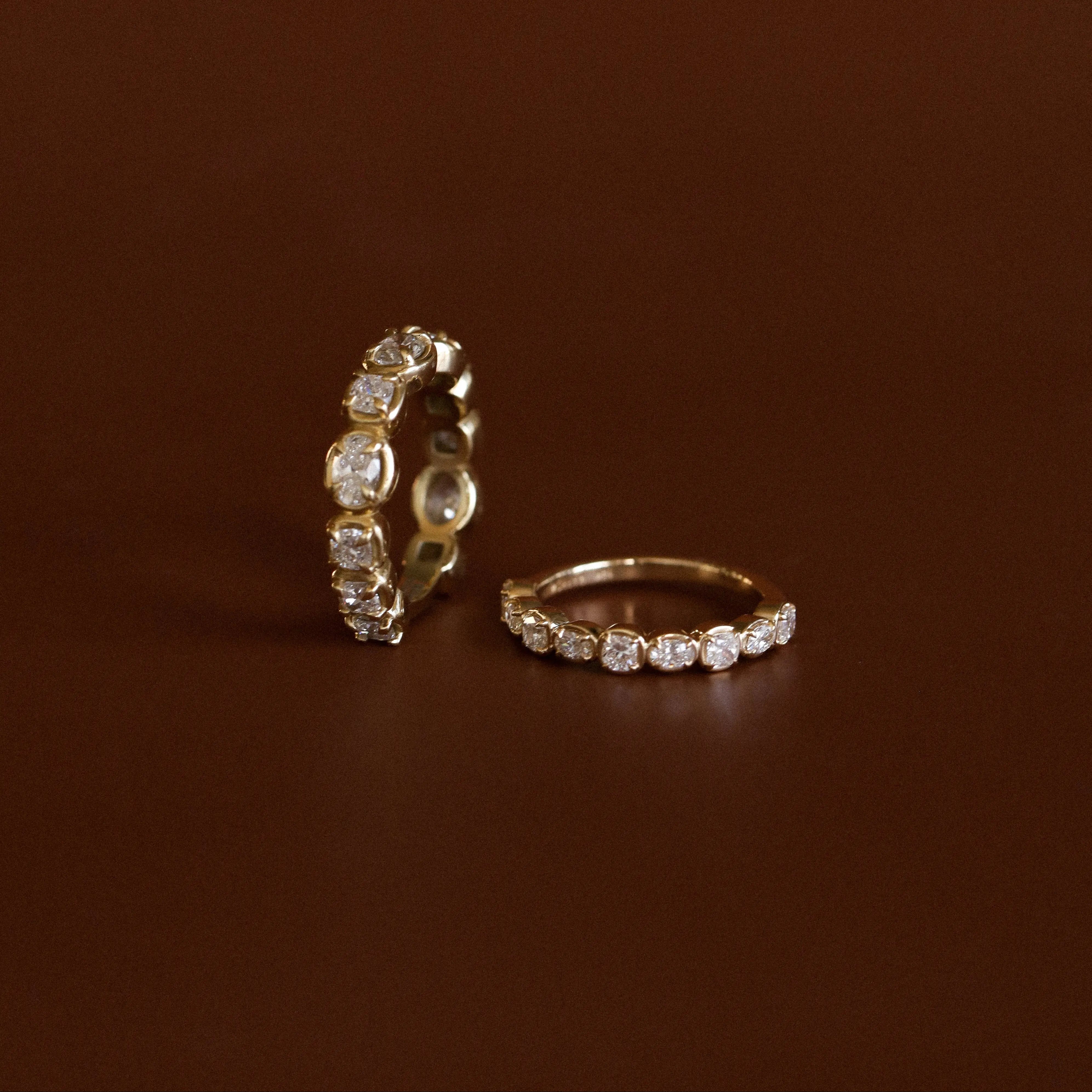 Two gold rings with diamond accents on a brown background