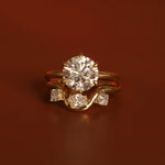 Gold ring with a large diamond and smaller diamonds on a brown background