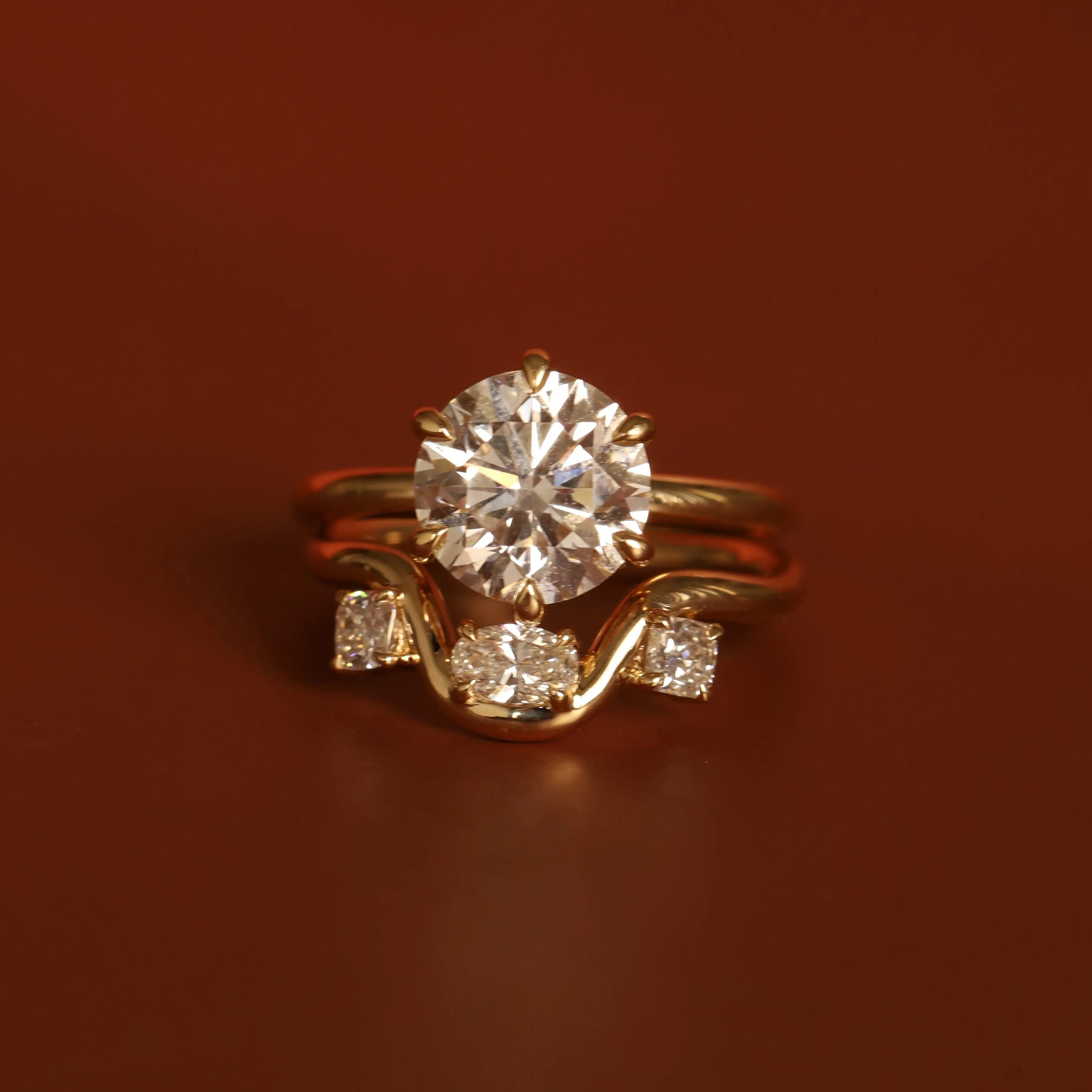 Gold ring with a large diamond and smaller diamonds on a brown background