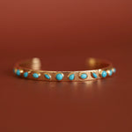 Gold bracelet with turquoise stones on a brown background