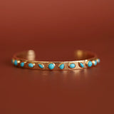 Gold bracelet with turquoise stones on a brown background