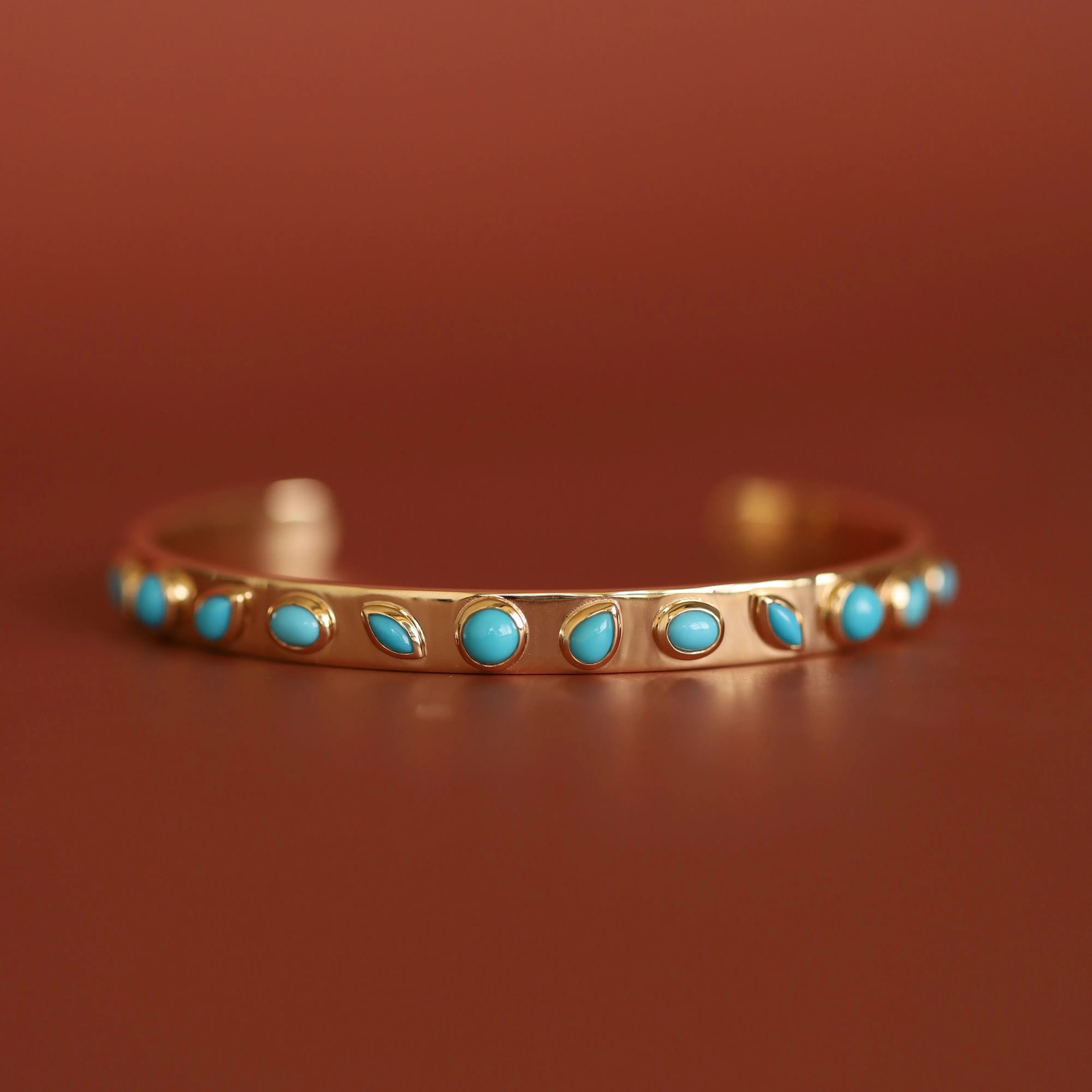 Gold bracelet with turquoise stones on a brown background