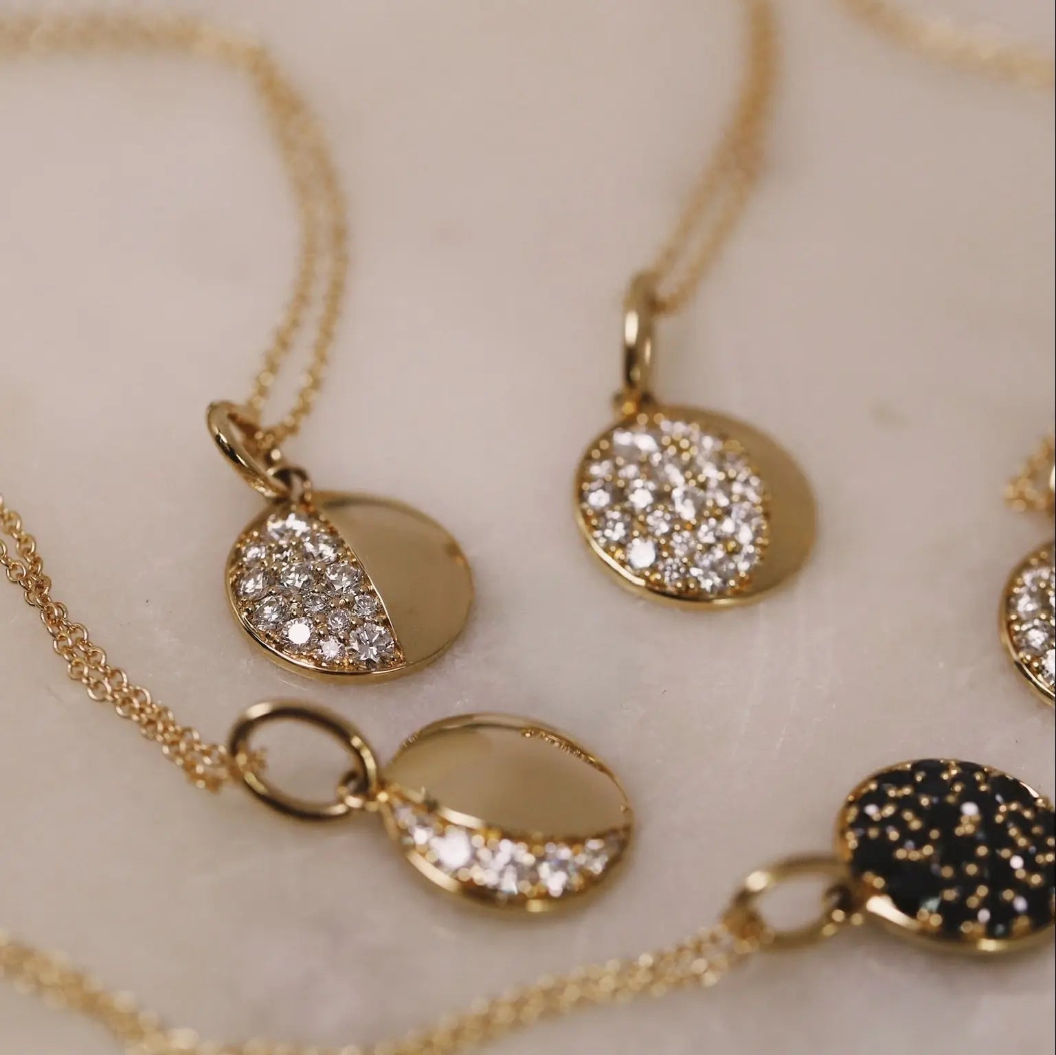Gold necklaces with circular pendants on a light background