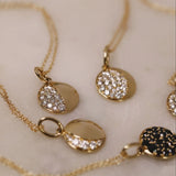 Gold necklaces with circular pendants on a light background