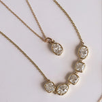 Gold necklace with diamond pendants on a light gray background