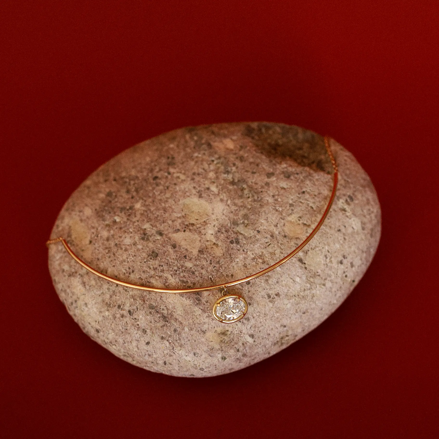 Odette oval collar styled on a rock against a red background