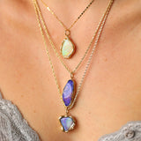 Necklace with opal pendants on a person wearing a gray top.