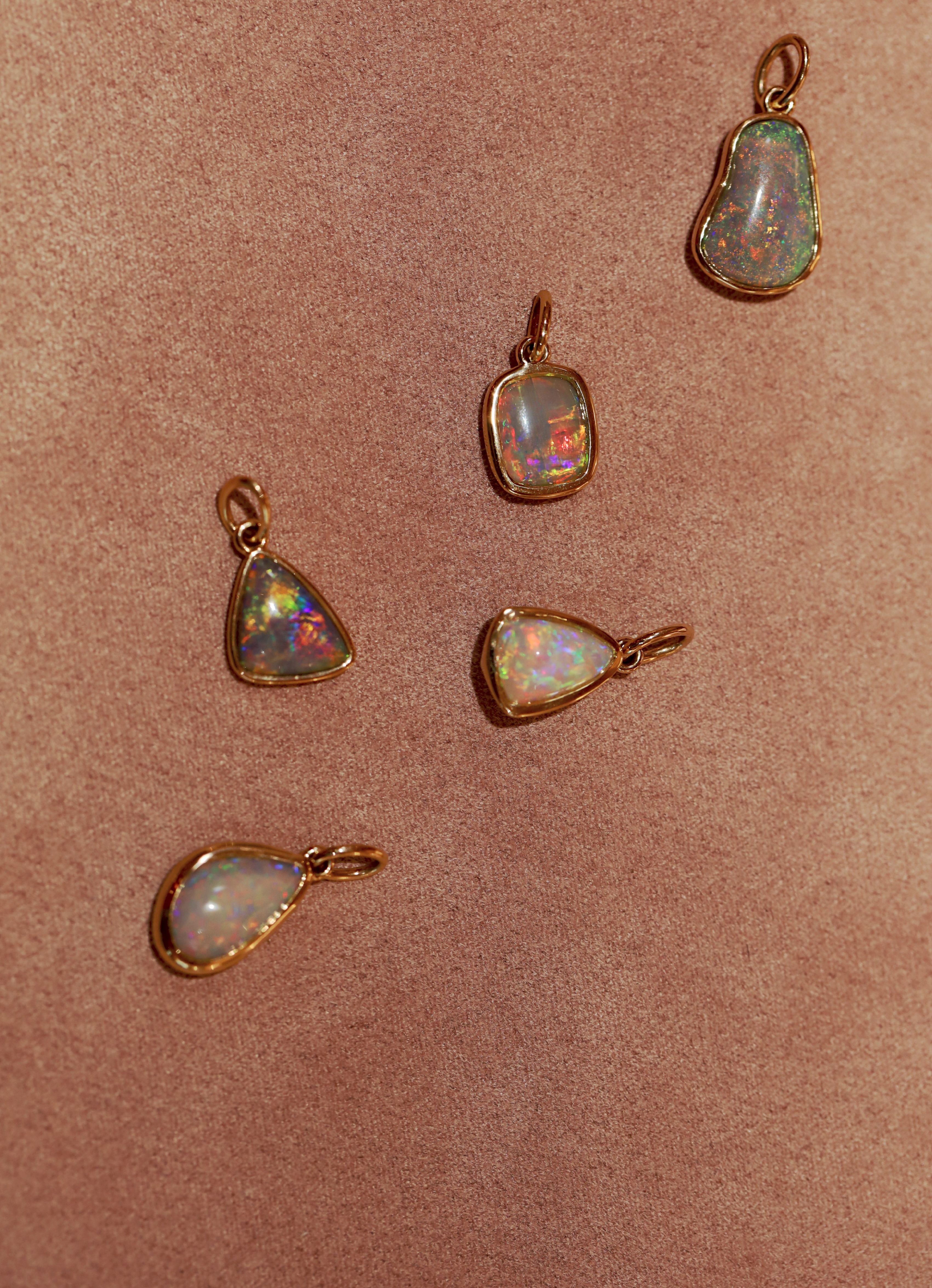 Five opal pendants on a pink background