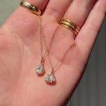 hand holding Lisse North/South Diamond Charm and East/West Diamond Charm