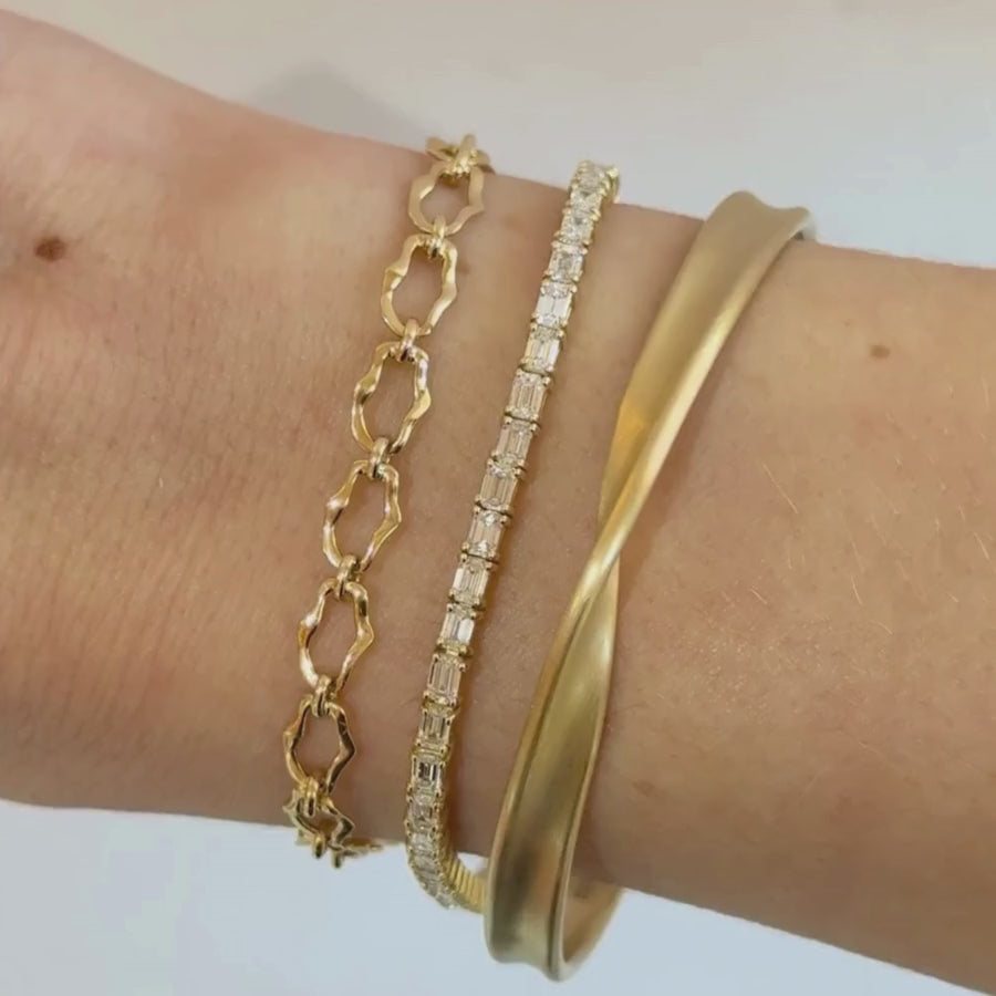 video of 2 solid gold bracelets and 1 tennis bracelet on woman's wrist against a white background